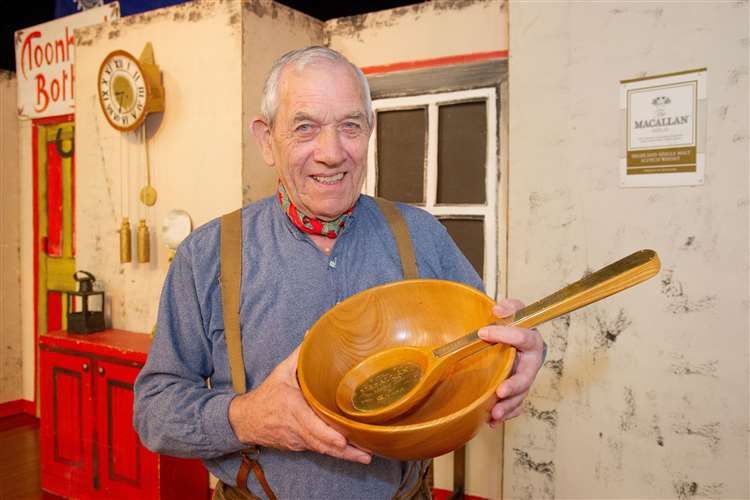Joe Aitken standing holding a wooden bowl and large spoon