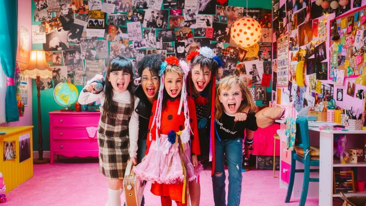 Small girls in a pink bedroom covered with pop posters