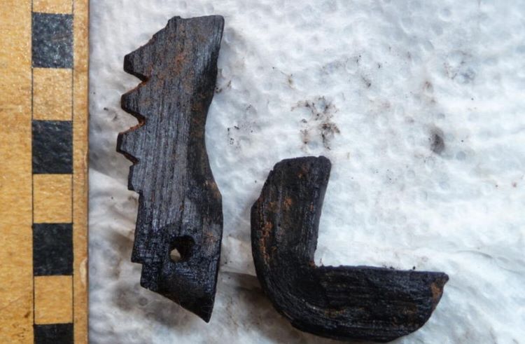 Burnt fragment with notches and a ruler showing scale - object size about 4 inches